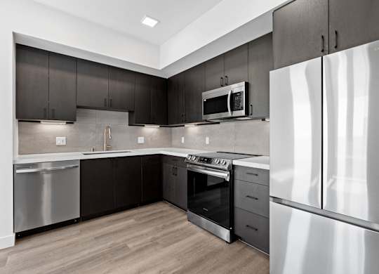 Sleek kitchen with stainless steel refrigerator and range at AMP 30 Apartments, San Diego