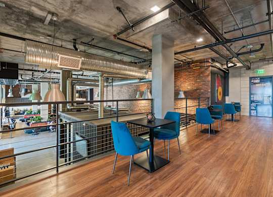 Mezzanine seating area with exposed ductwork and brick at AMP 30 Apartments, San Diego, CA