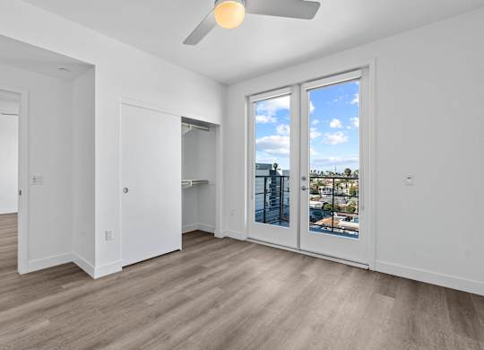 Empty bedroom with closet and balcony doors at AMP 30 Apartments, San Diego, California