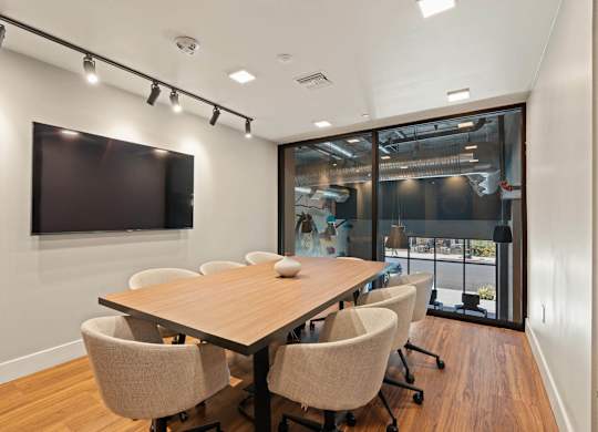Conference room with large screen and wood table at AMP 30 Apartments, San Diego