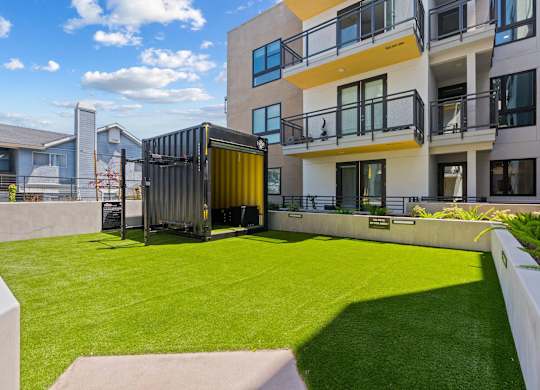 Courtyard with artificial turf and shipping container feature at AMP 30 Apartments, San Diego, California