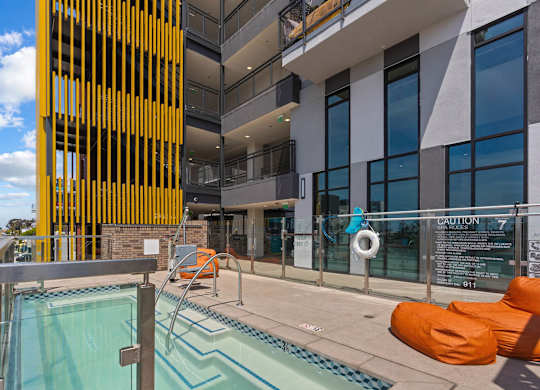 Rooftop pool area with spa and orange lounge seating at AMP 30 Apartments, San Diego, 92116