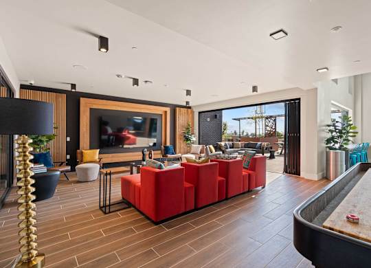 Resident lounge with red seating and outdoor patio access at AMP 30 Apartments, California