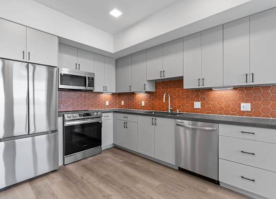 Modern kitchen with orange hexagon tile backsplash at AMP 30 Apartments, San Diego, 92116
