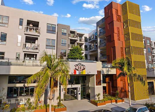 Building entrance with colorful tower and palm trees at AMP 30 Apartments, California