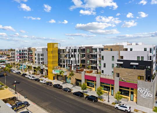 Modern mixeduse development with colorful facades and street parking at AMP 30 Apartments, California