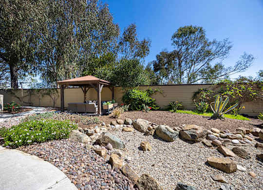 A house with a patio and a rock garden in front.
