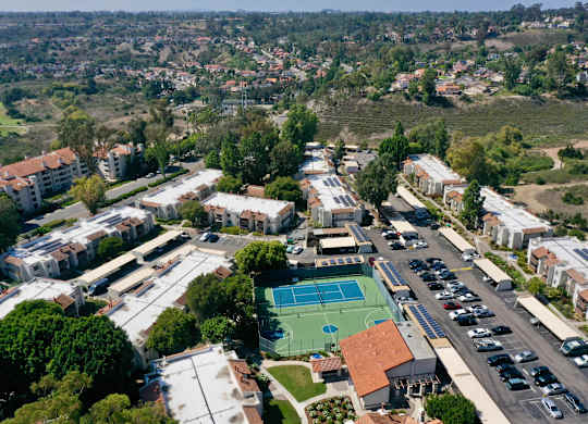 A view of a school with a basketball court and a parking lot.