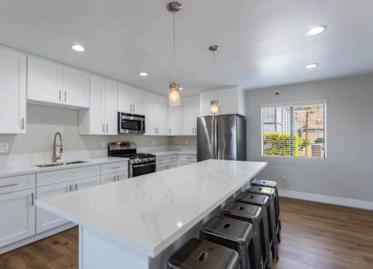 A kitchen with white cabinets and a marble countertop.