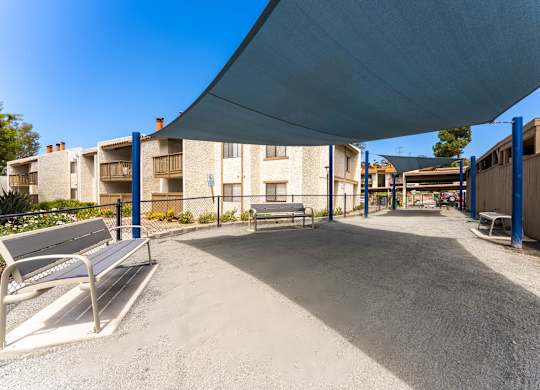 A playground with a blue canopy and a bench is in the foreground.