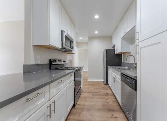 A modern kitchen with white cabinets and stainless steel appliances.