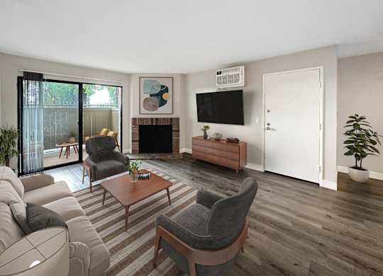 A living room with a grey sofa, a grey armchair, a wooden coffee table, a fireplace, and a television on the wall.