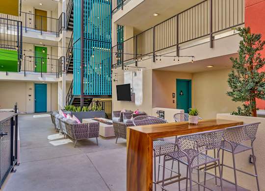 A patio with a table and chairs is surrounded by a metal fence.