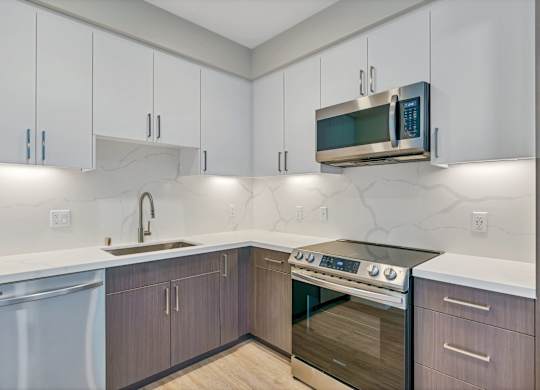 A modern kitchen with a stainless steel oven and white cabinets.
