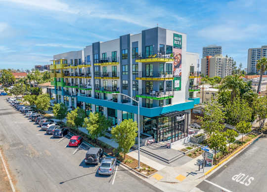 A street view of a multi-story building with a parking lot in front.