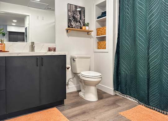 Bathroom with dark vanity and wood laminate flooring at AMP 30 Apartments, San Diego