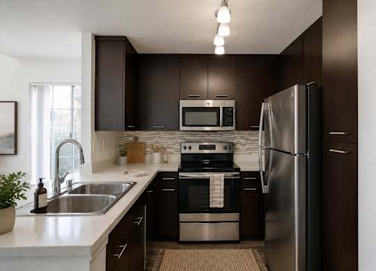 A modern kitchen with dark brown cabinets and stainless steel appliances.