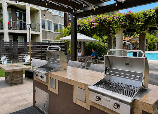 Two grills are on a counter with a pool in the background.