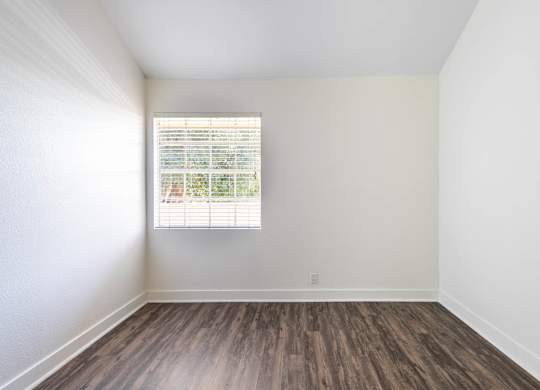 A room with a window and wooden flooring.