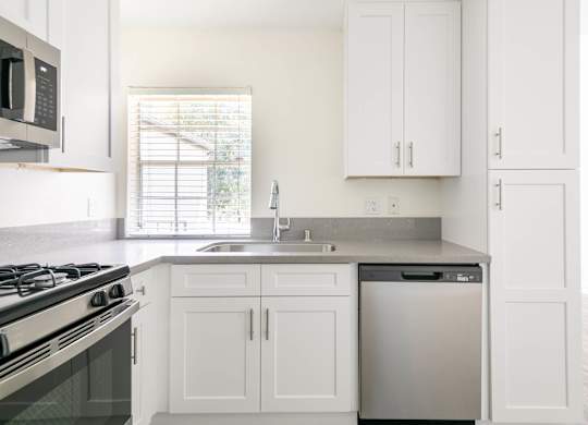 A kitchen with white cabinets and a black stove top.