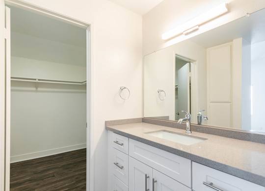 A bathroom with a sink, mirror, and a walk-in shower.
