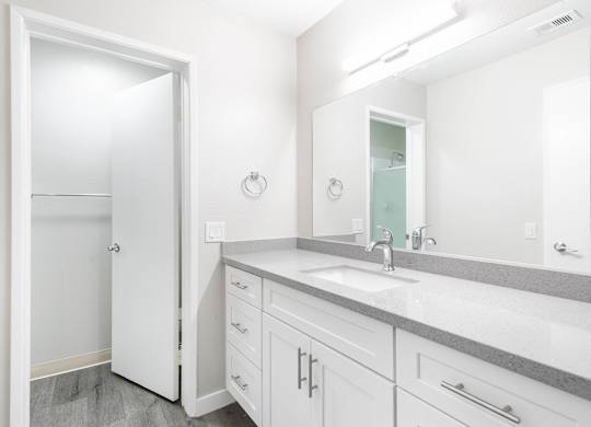A white bathroom with a sink and mirror.