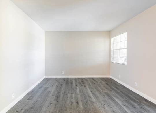 A room with wooden flooring and a window on the wall.