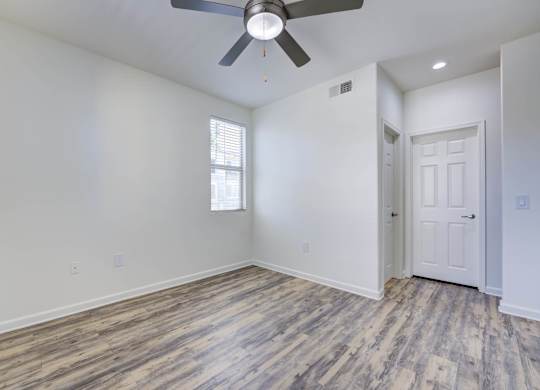 A room with a ceiling fan and a door.