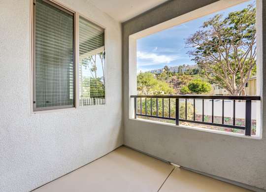 A balcony with a view of trees and a fence.