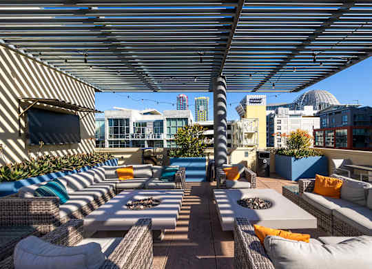 A rooftop patio with a striped awning and a fire pit.