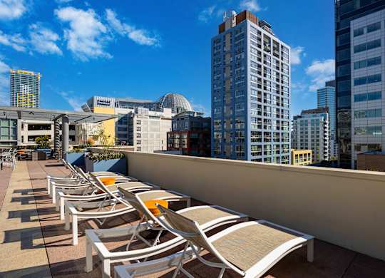A row of sun loungers on a balcony overlooking a city.