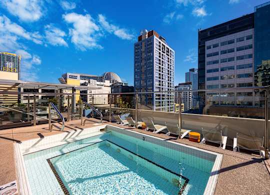 A swimming pool on a rooftop with a cityscape in the background.
