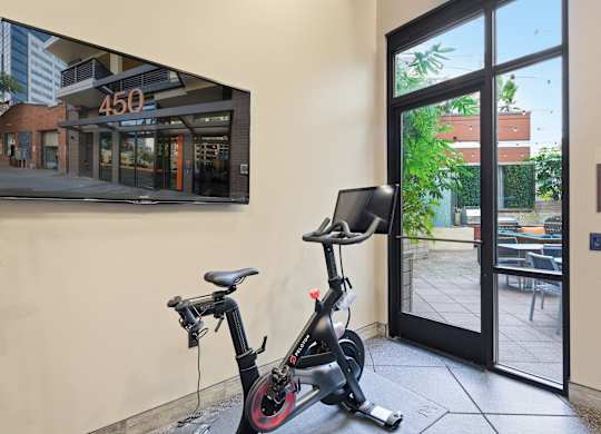 A stationary bike is in a room with a picture of a building with the number 450 on it.