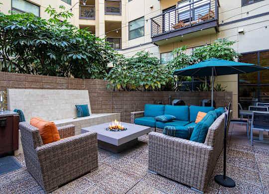 A patio with a fire pit and wicker furniture.