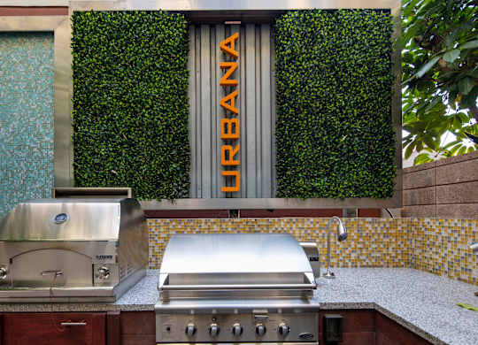 A grill is on a counter in front of a green wall.