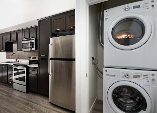 A modern kitchen with a stainless steel refrigerator and a white washing machine.