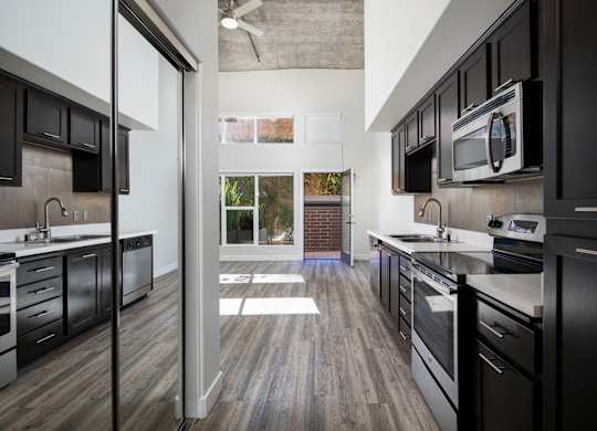A modern kitchen with black cabinets and stainless steel appliances.