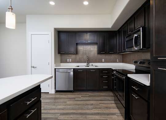 A modern kitchen with dark wood cabinets and white countertops.