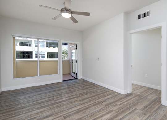 A room with a ceiling fan and a door leading to another room.