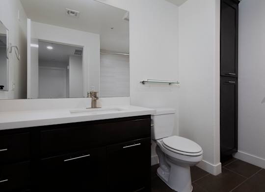 A white toilet sits in a bathroom with black cabinets.