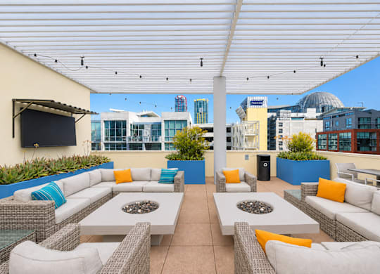 Rooftop terrace with sectional seating and fire tables at Urbana Apartments, California, 92101