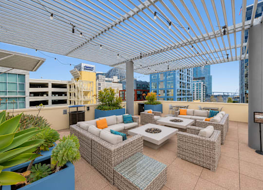 Rooftop patio with wicker furniture and fire pit tables at Urbana Apartments, San Diego, 92101