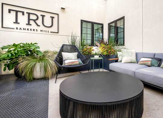 A black round table is in the middle of a patio with a couch and chairs.