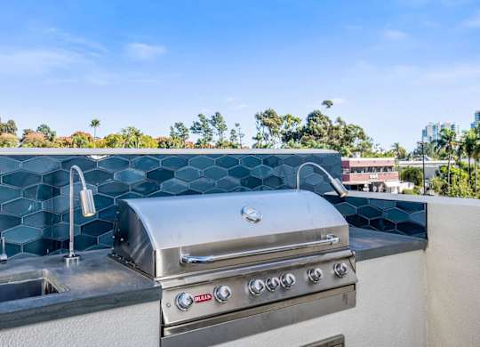 A modern outdoor kitchen with a stainless steel grill and sink.