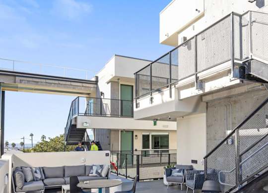 A modern outdoor patio with a metal railing and a couch.