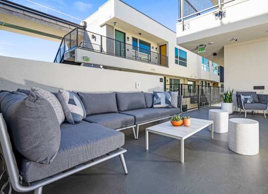 A modern outdoor seating area with grey couches and a white coffee table.