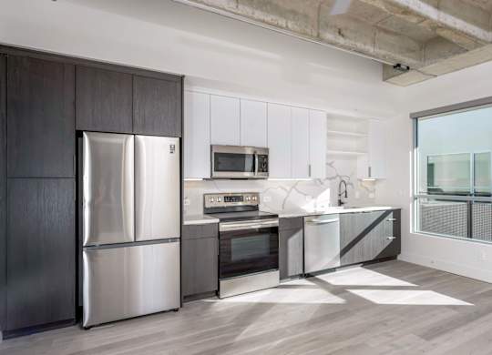 A modern kitchen with a stainless steel refrigerator and microwave.