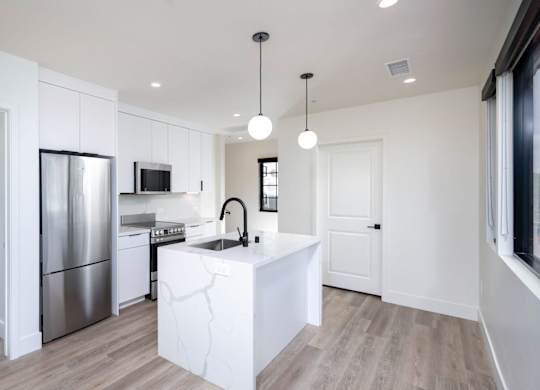 A modern kitchen with a white island and stainless steel appliances.