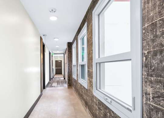A long hallway with windows on the side and a door at the end.
