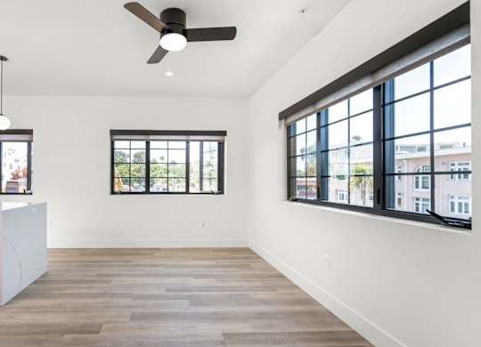 A kitchen with a stainless steel trash can and wooden flooring.
